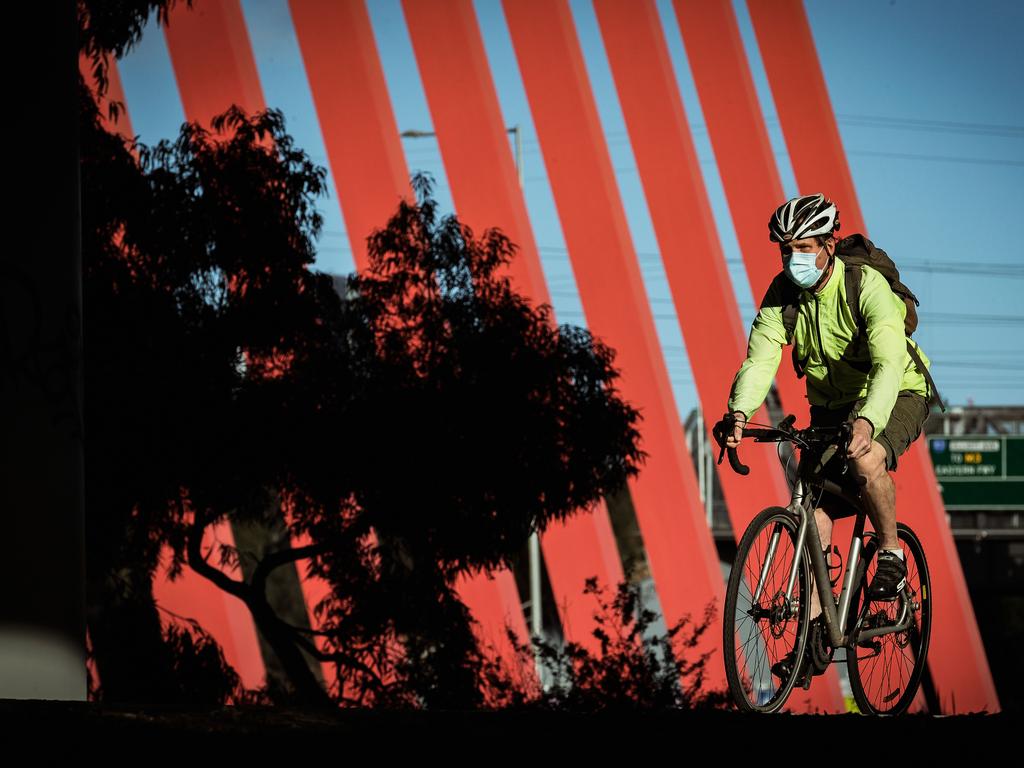 A man wearing a face mask is seen riding a bike in Melbourne on Monday. Picture: Darrian Traynor