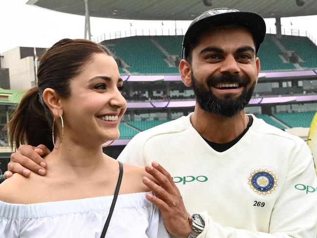 (FILES) In this file photo taken on January 07, 2019 India's captain Virat Kolhi and his wife Anushka Sharma walk on the field as they celebrate India's series win on the fifth day of the fourth and final cricket Test against Australia at the Sydney Cricket Ground in Sydney. - Virat Kohli having his hair cut by his Bollywood wife, to Ravindra Jadeja on a stallion, India's superstar cricketers are making the most of their enforced break during the national coronavirus lockdown. The Indian government imposed a 21-day lockdown on March 24, 2020, as a preventive measure against the spread of the COVID-19 novel coronavirus. (Photo by Peter PARKS / AFP)