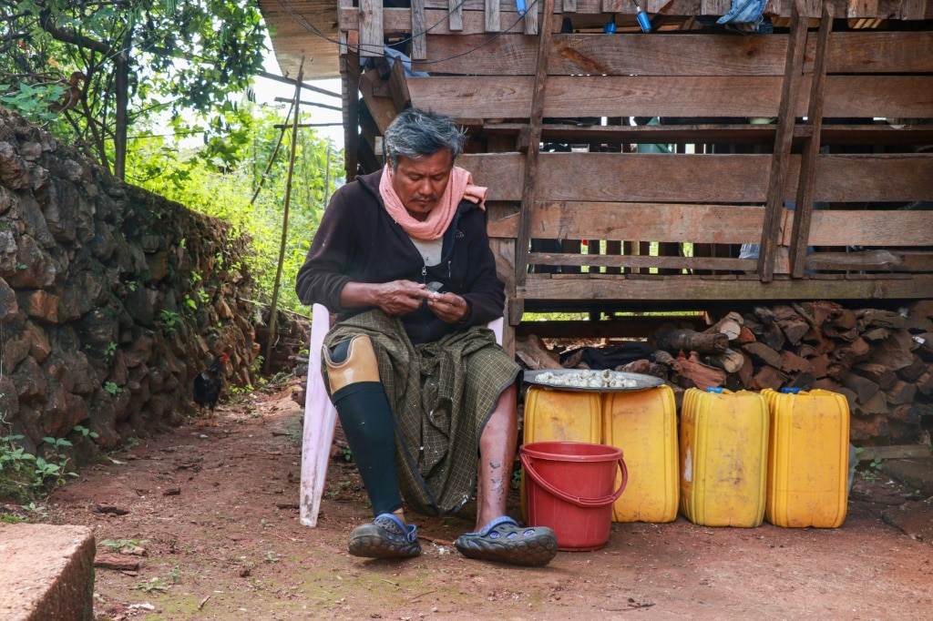 Farmer Hla Han, 52, who lost his leg after stepping on a mine, sits outside his house in Demoso township, eastern Kayah state