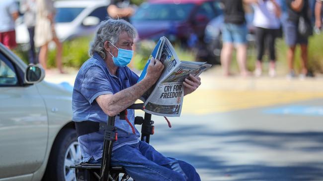 A man reads the paper as long lines formed across Shepparton to be tested for the virus. Picture: Alex Coppel.