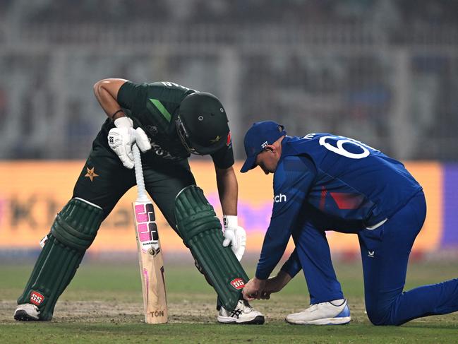 England's Joe Root (R) ties the shoelace of Pakistan's Mohammad Rizwan during the 2023 ICC Men's Cricket World Cup one-day international (ODI) match between England and Pakistan at the Eden Gardens in Kolkata on November 11, 2023. (Photo by Arun SANKAR / AFP) / -- IMAGE RESTRICTED TO EDITORIAL USE - STRICTLY NO COMMERCIAL USE --