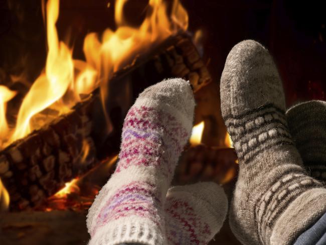 Couple relaxing at the fireplace on winter evening. Istock image for Herald Sun real estate section.