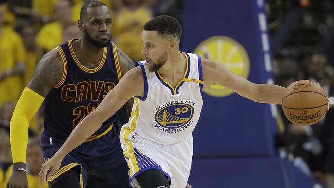 Golden State’s Stephen Curry keeps the ball off Cleveland’s LeBron James