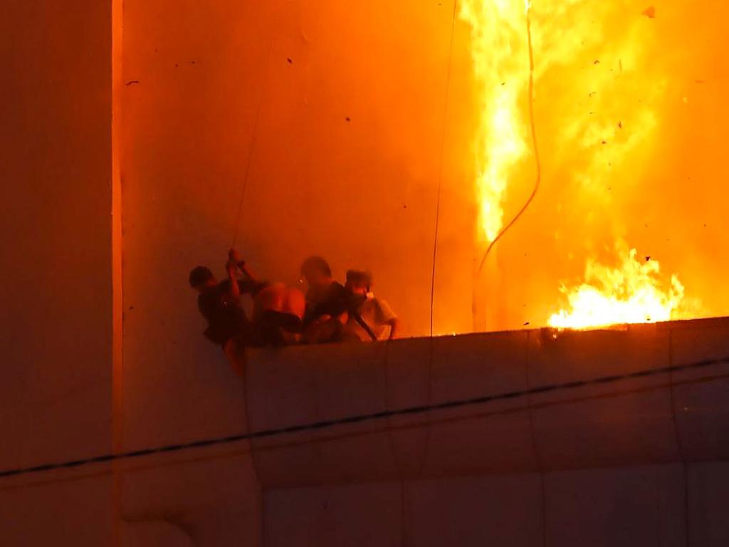 People gather on a ledge as a fire burns around them at the Grand Diamond City hotel-casino. Picture: AFP