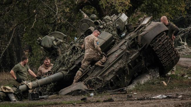 Ukrainian soldiers scavenge an abandoned Russian T-90A tank in Kyrylivka, near Kharkiv. Picture: AFP