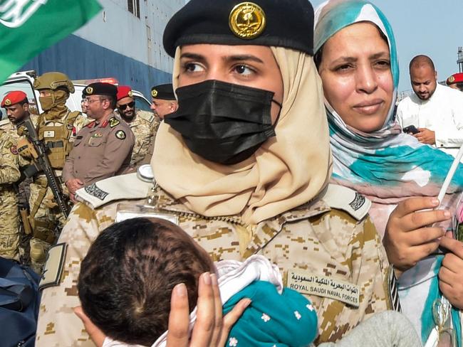 TOPSHOT - A Saudi Navy sailor carries a child as evacuees arrive at King Faisal Navy Base in Jeddah on April 26, 2023, following a rescue operation from Sudan. - A ship carrying 1,687 civilians from more than 50 countries fleeing violence in Sudan docked in Saudi Arabia on April 26, the foreign ministry said, the largest evacuation effort by the Gulf kingdom so far. (Photo by Amer HILABI / AFP)