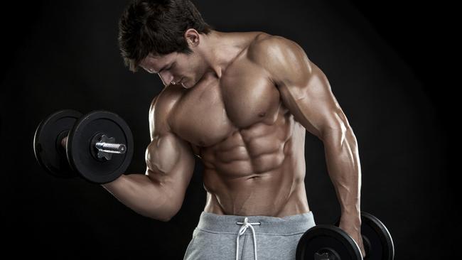 Muscular bodybuilder guy doing exercises with dumbbells