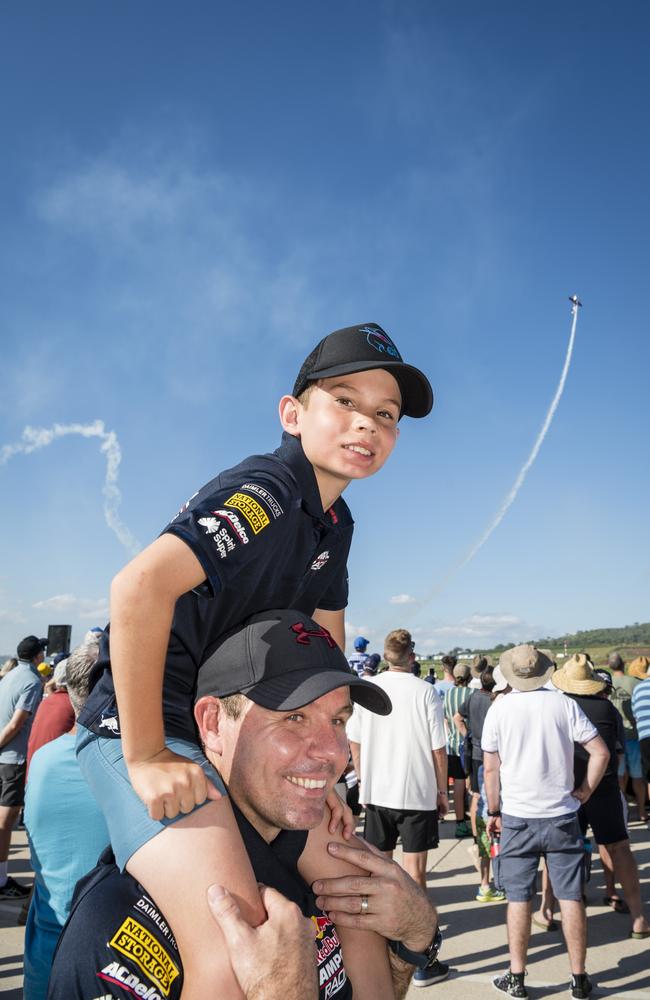 Chris Rogers and son Logan Rogers watch as Red Bull pilot Matt Hall wows the crowd with an aerobatic display as V8 Supercars team Red Bull Ampol Racing launch their 2024 livery at Toowoomba Wellcamp Airport, Saturday, February 3, 2024. Picture: Kevin Farmer