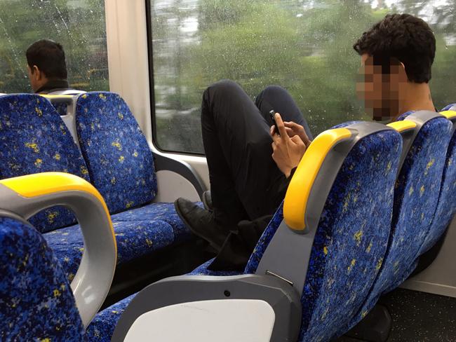 A passenger has his feet up on the seat during a train trip from Ashfield to the City. Picture: Craig Wilson