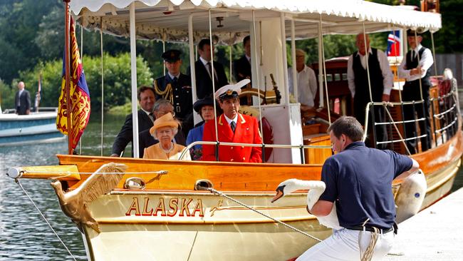 Queen Elizabeth II, accompanied by Swan Marker David Barber (red jacket), watches from the steam launch 'Alaska' as a swan upper places a swan back into the river during a swan upping census. Picture: Getty Images.