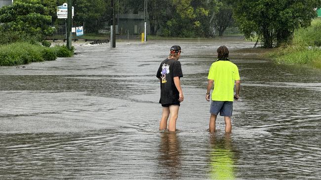 Locals testing the depths of the water over the service road flooded by Martins Creek at Kunda Park. Picture – Mark Furler.