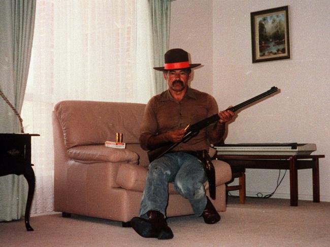 Ivan Milat convicted of the murders of seven backpackers, wearing a sheriff's badge, poses in his lounge room with firearms.