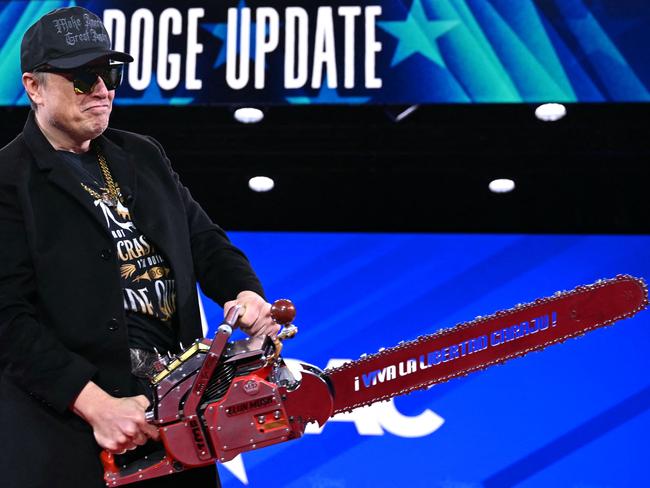 Elon Musk holds a chainsaw reading 