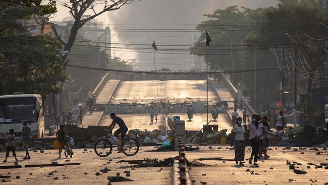 People walk past makeshift barricades set up by protesters to block a road during demonstrations against the military coup in Yangon. Picture: AFP