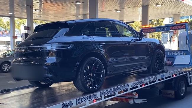 A black Porsche is towed away along St Kilda Rd.