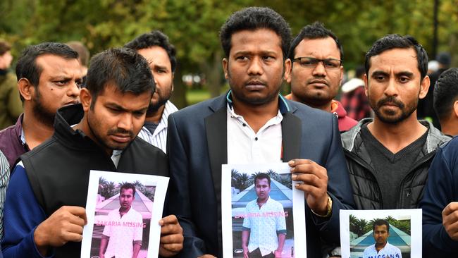 Friends of a missing man Zakaria Bhuiyan hold up photos of him outside a refuge centre in Christchurch. Picture: AAP