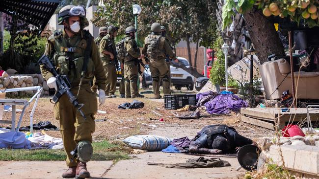 Israeli soldiers stand near the body of a Palestinian militant in Kfar Aza on October 10. Picture: AFP