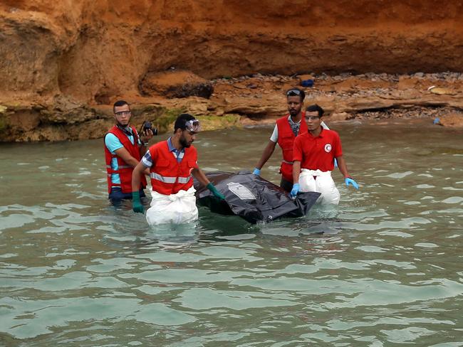 Members of the Libyan Red Crescent recover the body of a drowned migrant off the coast of Tajoura, east of the capital Tripoli, on July 3, 2018. At least seven migrants including two children died when their boat ran into trouble on July 3 off the coast of Libya, the coastguard said, the latest victims of the perilous voyage to Europe. / AFP PHOTO / Mahmud TURKIA