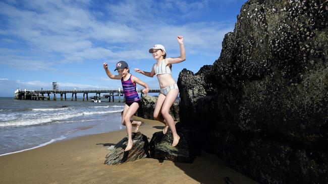 The lowest tide of the year has seen a lot of sand exposed on Palm Cove beach and left the jetty pylons high and dry. Sisters Alyse Tyrkalo, 8, and Ella Tyrkalo, 10, play on barnacle encrusted rocks that are usually underwater on Palm Cove beach. Picture: Brendan Radke