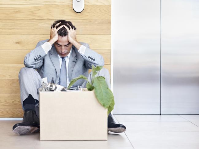 Portrait of a depressed manager sitting with head in hands as he waits for an elevator