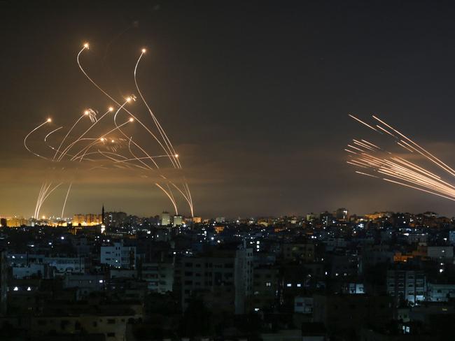 TOPSHOT - The Israeli Iron Dome missile defence system (L) intercepts rockets (R) fired by the Hamas movement towards southern Israel from Beit Lahia in the northern Gaza Strip as seen in the sky above the Gaza Strip overnight on May 14, 2021. - Israel bombarded Gaza with artillery and air strikes on Friday, May 14, in response to a new barrage of rocket fire from the Hamas-run enclave, but stopped short of a ground offensive in the conflict that has now claimed more than 100 Palestinian lives. As the violence intensified, Israel said it was carrying out an attack "in the Gaza Strip" although it later clarified there were no boots on the ground. (Photo by ANAS BABA / AFP)