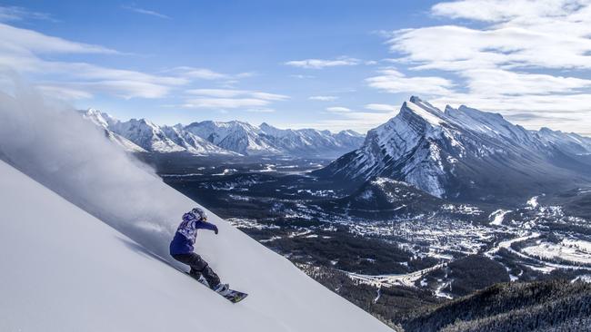 A lone snowboarder carves it up on Mount Norquay.