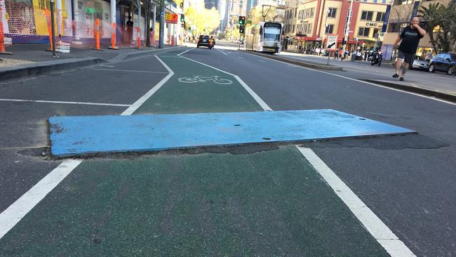 A steel plate straddling a bicycle lane on Swanston St, Melbourne.