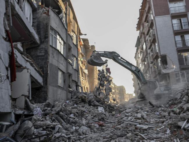 An excavator clears debris amidst collapsed buildings in Hatay on February 15, 2023, nine days after a 7,8-magnitude earthquake struck parts of Turkey and Syria. (Photo by BULENT KILIC / AFP)