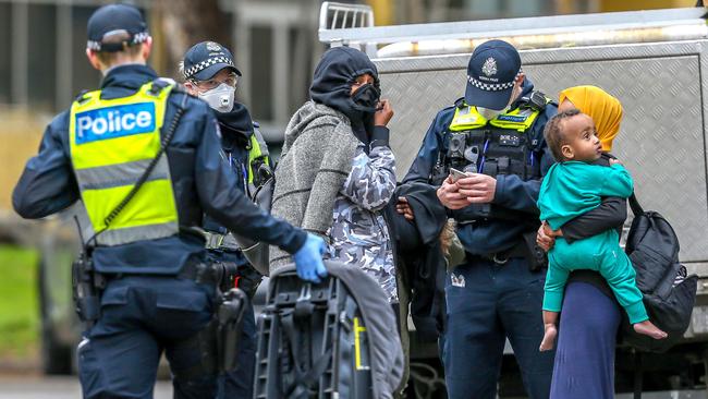 Police speak with two women and a child outside of the Housing Commission towers. Picture: Tim Carrafa