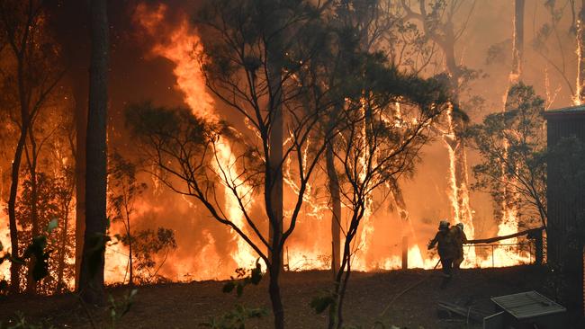 RFS volunteers and NSW Fire and Rescue officers protect a home on Wheelbarrow Ridge Road being impacted by the Gospers Mountain fire near Colo Heights. Picture: AAP