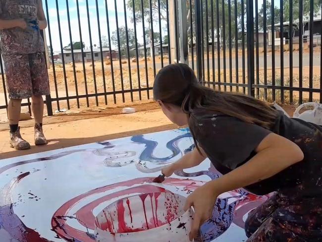 Rosie Palmer, manager of the Tjala Arts centre in the APY Lands of South Australia, is seen appearing to paint on the work of Indigenous artist Yaritji Young.