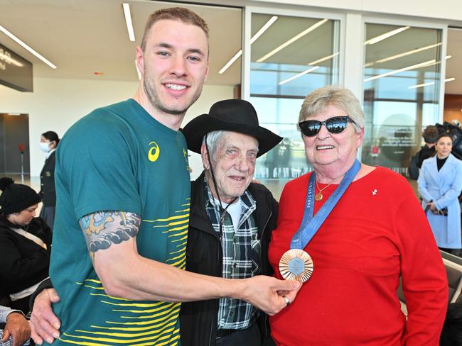 South Australian Olympic cyclist Leigh Hoffman with his Aunty Phyll and uncle Neil Martin with his bronze medal at Adelaide Airport. Picture: NewsWire / Brenton Edwards