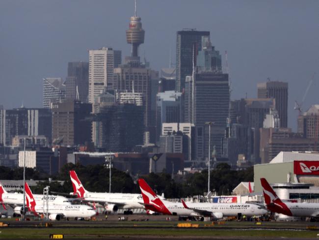 This picture taken on December 6, 2023 shows the Sydney central business district (CBD) behind Qantas Airways passenger aircraft parked at the Sydney domestic airport. (Photo by DAVID GRAY / AFP)