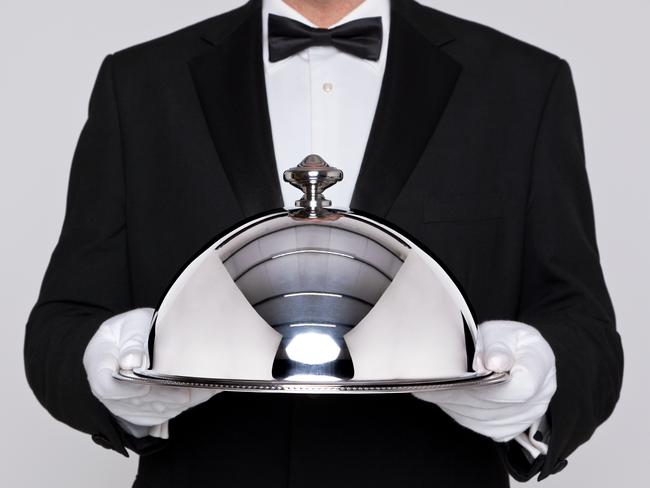 Waiter serving a meal under a silver cloche or dome