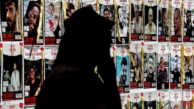 A protester in Tel Aviv walking past posters of hostages on Thursday. Picture: Jack Guez/AFP