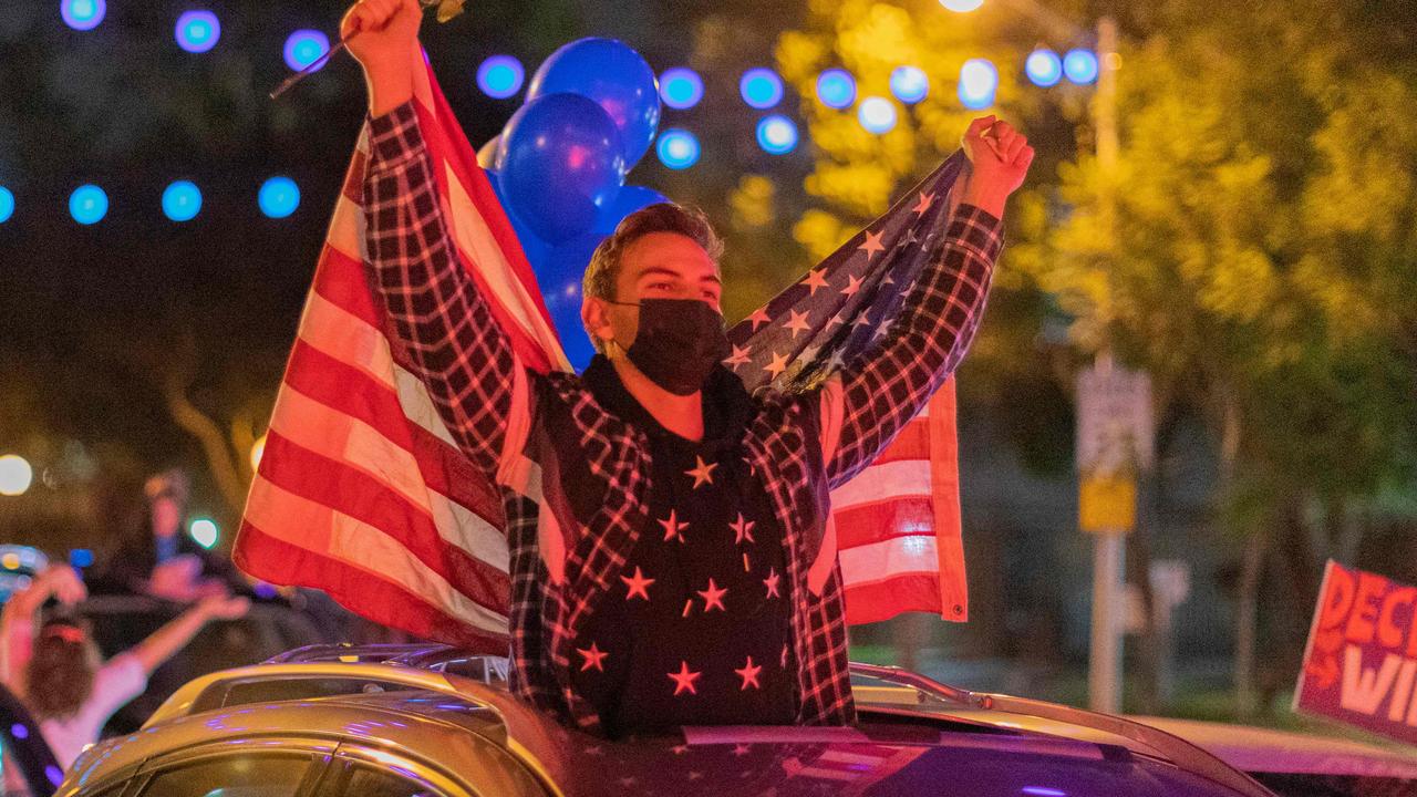 TOPSHOT - People celebrate the victory of Joe Biden in the 2020 presidential election in West Hollywood, California, on November 7, 2020. - Democrat Joe Biden urged unity on November 7 and promised "a new day for America" in his first national address since he won the tense US election and ended the historically turbulent and divisive era of Donald Trump. (Photo by DAVID MCNEW / AFP)