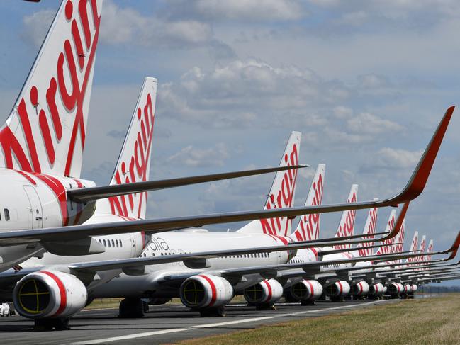 Grounded Virgin Australia aircraft are seen parked at Brisbane Airport in Brisbane, Tuesday, April 7, 2020. Brisbane Airport Corporation (BAC) is working with airlines by accommodating up to 100 grounded aircraft free of charge in response to government-mandated travel restrictions that have grounded a significant proportion of Australia's airline fleet because of the Coronavirus (COVID-19). (AAP Image/Darren England) NO ARCHIVING