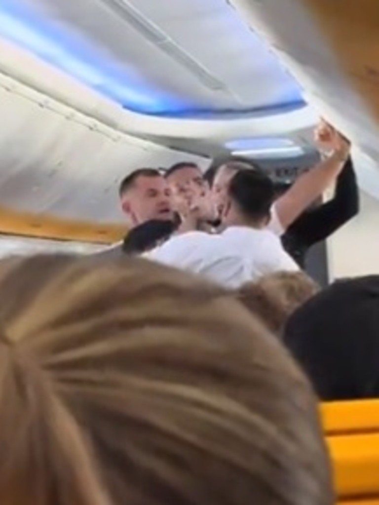 A man could be seen trying to open an overhead compartment as cabin crew try to stop it. Picture: Facebook/Canal 4 Tenerife