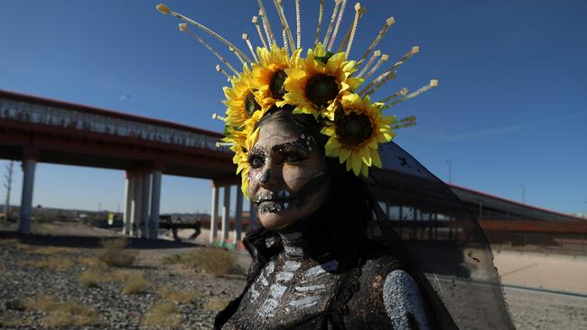 A Mexican migrant seeking asylum in the United States dressed as a Catrina stands next to a bridge in the Mexico-United States border as she takes part in the Festival of Living Migrant Skulls in Ciudad Juarez, Chihuahua state, Mexico, on October 31. Picture: Herika Martinez / AFP