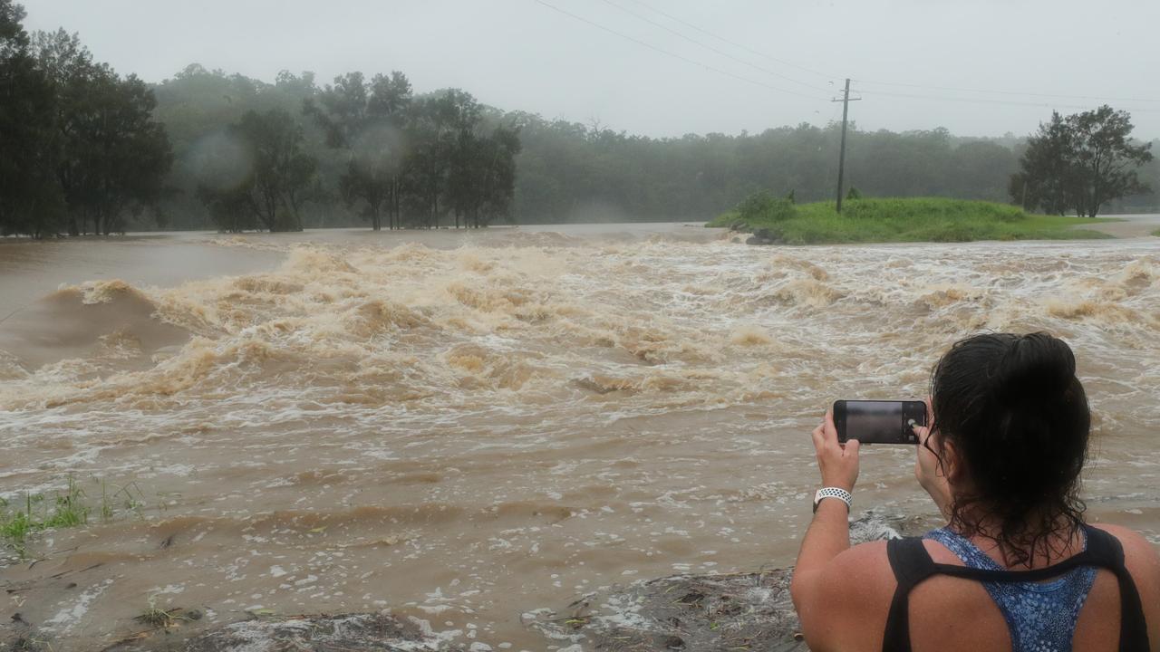 Oxenford local Cheryl Glanz records the floodwater pour over the Oxenford Weir. Picture: Glenn Hampson