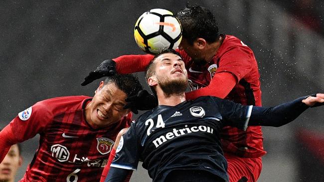 Melbourne Victory’s Terry Antonis competes for the ball with two Shanghai SIPG defenders.
