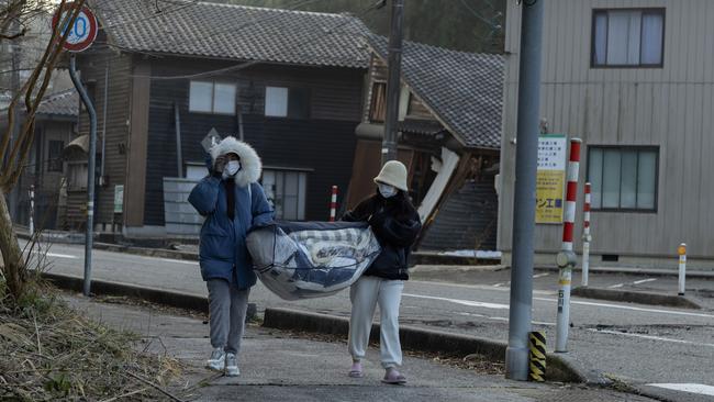 Local residents carry their belongings through an earthquake damaged area on January 02, 2024 in Nanao, Japan. The Noto Peninsula of Ishikawa Prefecture was struck by a 7.5 magnitude earthquake on New Year’s Day. Picture: Getty Images