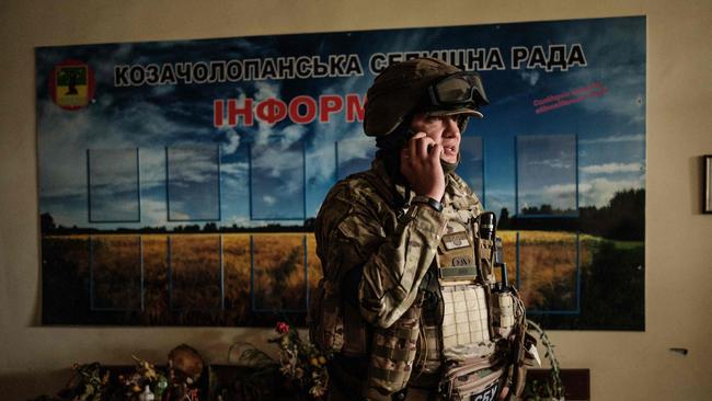 An unidentified Ukrainian soldier talks on his phone in the lobby of the local civil administration office in the retaken town of Kozacha Lopan,.