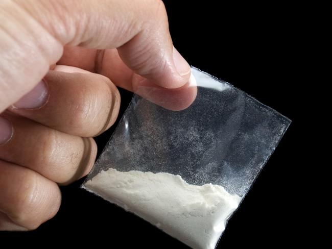 Generic photo of cocaine. Dealer is holding drug bag in his hand on a black background. Picture: iStock