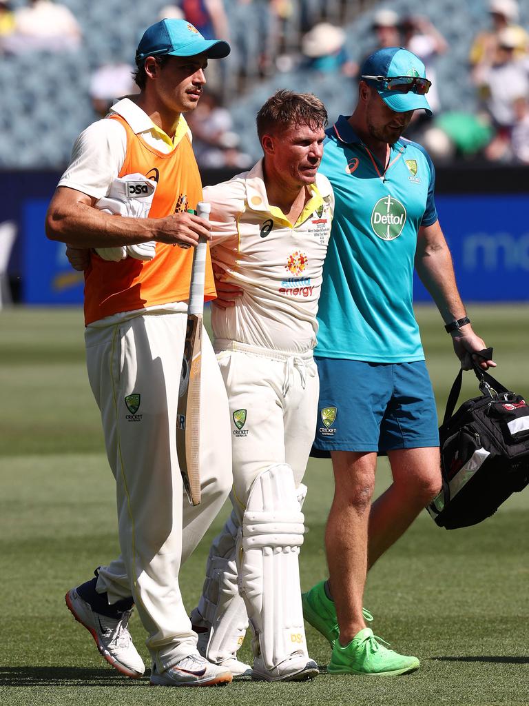 Warner is helped from the ground. Picture: Michael Klein