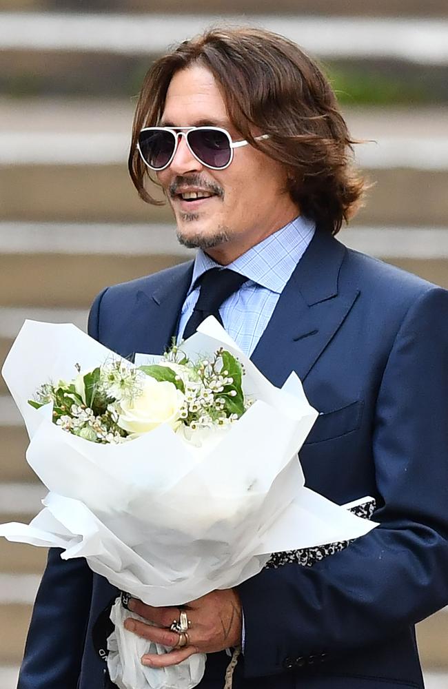 Johnny Depp clutching a floral bouquet given to him by fans outside court.