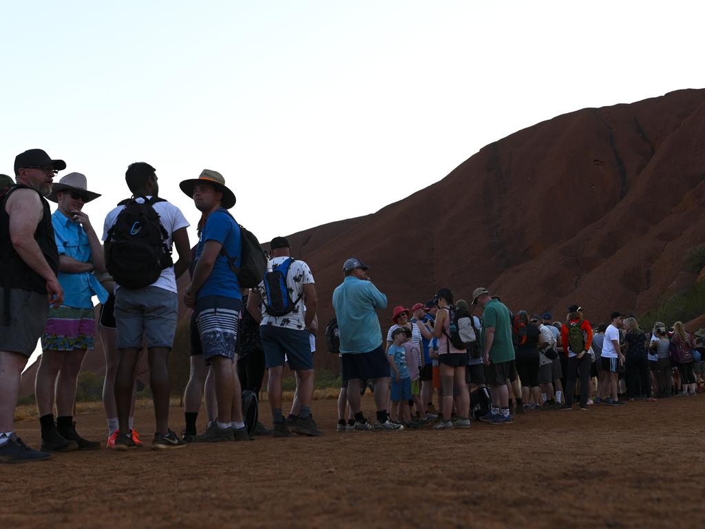 Tourists are seen lining up to climb Uluru, also known as Ayers Rock at Uluru-Kata Tjuta National Park in the Northern Territory, Saturday, October 12, 2019. Climbing Uluru will be banned starting from October 26, 2019. (AAP Image/Lukas Coch) NO ARCHIVING