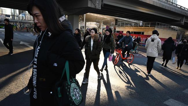 Commuters walk across a road in central Beijing  yesterday as news broke of the Chinese economy going off the boil. Picture: AFP