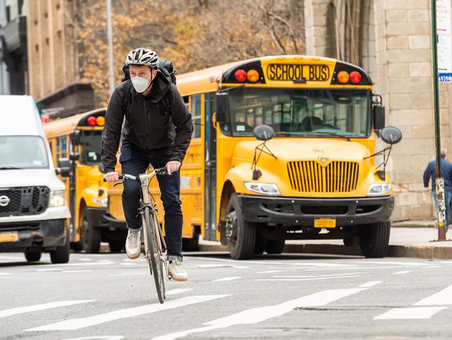 A person rides a bicycle by a school bus in Union Square, New York, as the city continues the reopening efforts. The US death toll has passed one million. Picture: Getty Images