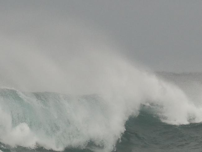 Large rough surf at Bondi Beach, surfers battle the waves and spectators watch the waves crash against the rocks. Picture Rohan Kelly